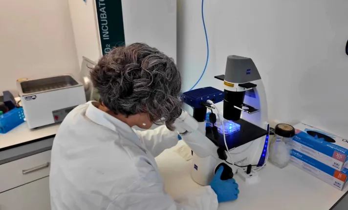 Mujer mirando por un microscopio en un laboratorio