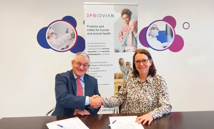 Dos personas sonrientes estrechan la mano sobre una mesa tras firmar documentos de 3pbiovian