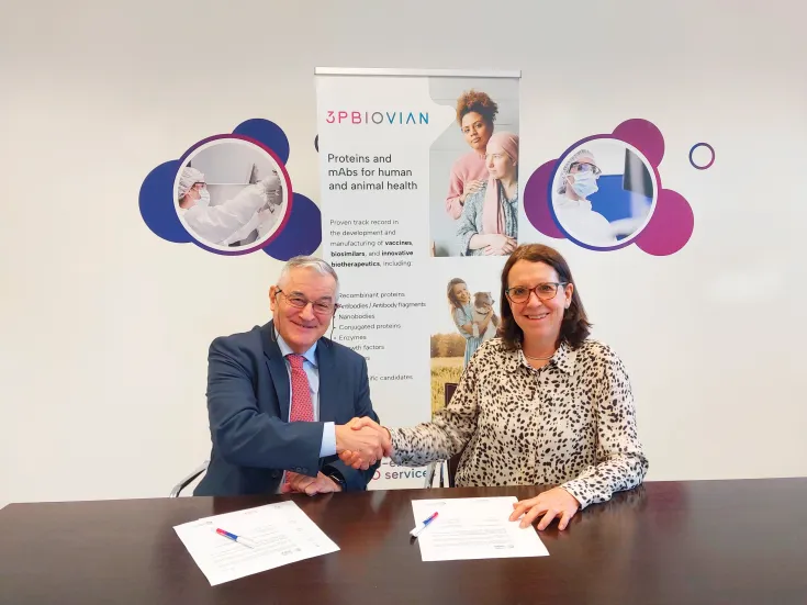 Dos personas sonrientes estrechan la mano sobre una mesa tras firmar documentos de 3pbiovian